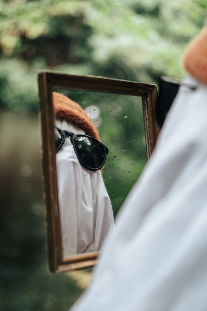 pexels photo 14056133 A spooky ghost wearing sunglasses and a hat is reflected in a mirror in the forest.