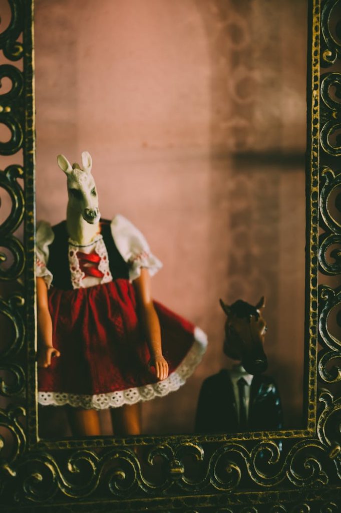 pexels photo 3613345 Quirky dolls in horse masks dressed in traditional wear seen through a detailed golden frame.